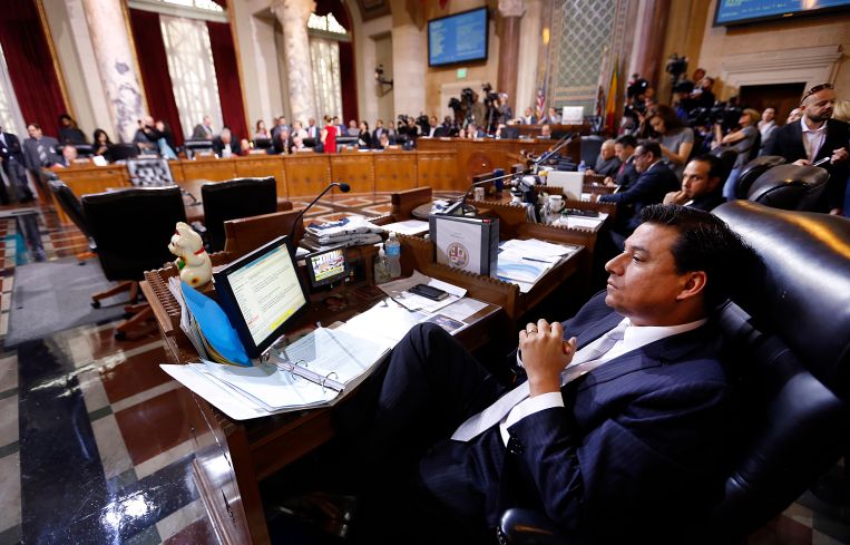 Former Los Angeles City Councilmember Jose Huizar, listens as speakers deliver arguments at Los Angeles City Hall. Former Councilman Mitch Englander sits behind him.