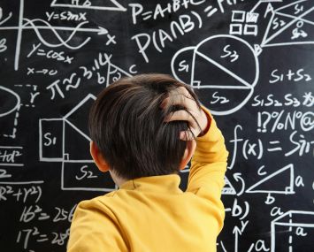 The little boy the blackboard scratching his head