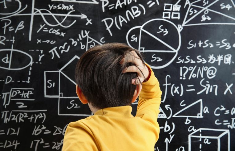 The little boy the blackboard scratching his head
