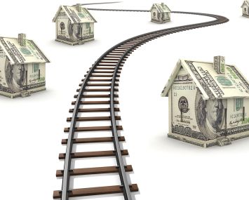 Railroad tracks running through houses made of money.