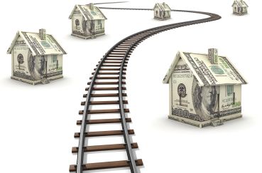 Railroad tracks running through houses made of money.