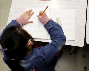 A New York City public school student draws on a piece of paper in class.