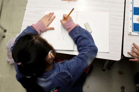 A New York City public school student draws on a piece of paper in class.