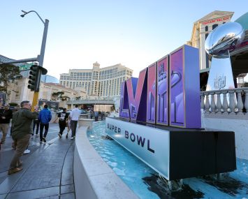 Visitors walk in front of a Super Bowl LVIII logo and an oversized replica of the Vince Lombardi Trophy on the Las Vegas Strip in front of Caesars Palace on Feb. 3 in Las Vegas.