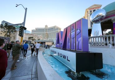 Visitors walk in front of a Super Bowl LVIII logo and an oversized replica of the Vince Lombardi Trophy on the Las Vegas Strip in front of Caesars Palace on Feb. 3 in Las Vegas. 