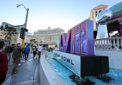 Visitors walk in front of a Super Bowl LVIII logo and an oversized replica of the Vince Lombardi Trophy on the Las Vegas Strip in front of Caesars Palace on Feb. 3 in Las Vegas. 