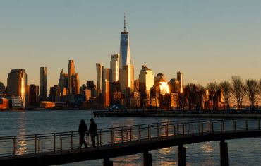 HOBOKEN, NJ - FEBRUARY 19: The sun sets on the skyline of lower Manhattan and One World Trade Center in New York City as people walk on a pier in the Hudson River on February 19, 2024, in Hoboken, New Jersey.  (Photo by Gary Hershorn/Getty Images)