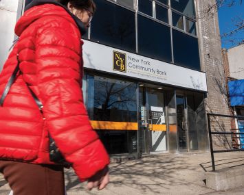 A pedestrian walks past a New York Community Bank branch in Brooklyn