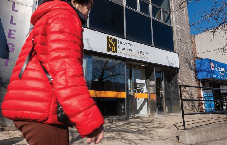 A pedestrian walks past a New York Community Bank branch in Brooklyn