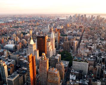 An aerial view of a big city with lots of buildings, at sunset.