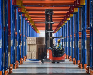 A worker operates a forklift at a logistics center.
