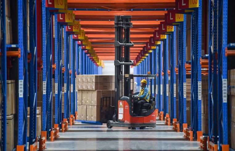A worker operates a forklift at a logistics center.