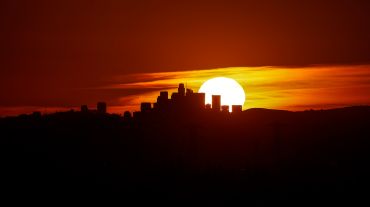 The sun sets behind the LA skyline as seen from Azusa.