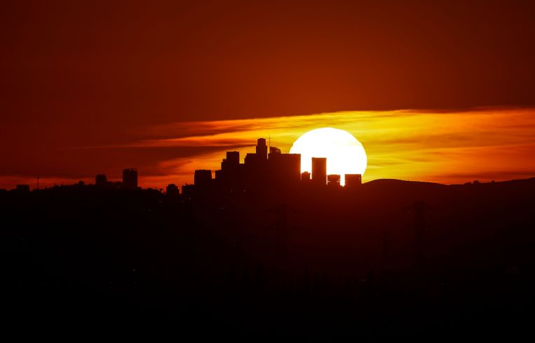 The sun sets behind the LA skyline as seen from Azusa.
