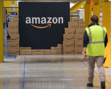 Amazon employee passes by its logo at a distribution center.