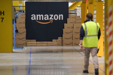 Amazon employee passes by its logo at a distribution center.