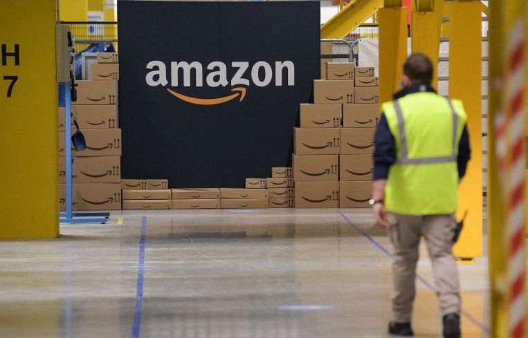 Amazon employee passes by its logo at a distribution center.