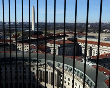 A view of the Washington Monument seen between wires that cover the windows on the observation deck of the Old Post Office Tower in Washington, DC.
