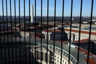 A view of the Washington Monument seen between wires that cover the windows on the observation deck of the Old Post Office Tower in Washington, DC.