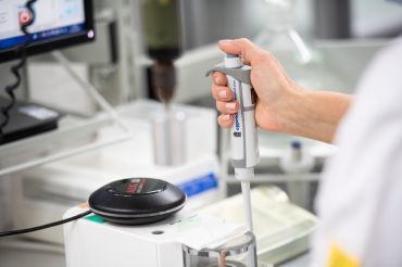 Employee works with a pipette in the quality control department of a medical technology manufacturer.