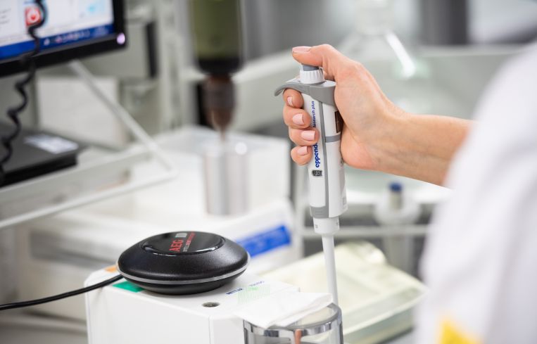 Employee works with a pipette in the quality control department of a medical technology manufacturer.