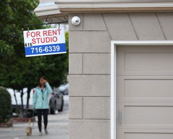 A sign is posted in front of an apartment building with available rentals.