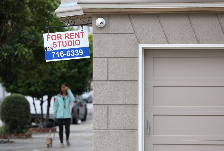 A sign is posted in front of an apartment building with available rentals.