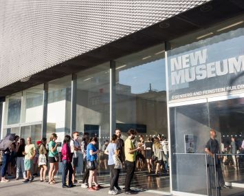 A small crowd of people lining up to enter the lobby of the New Museum in Manhattan.