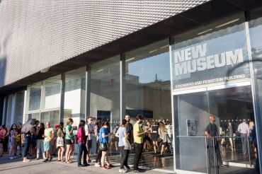 A small crowd of people lining up to enter the lobby of the New Museum in Manhattan.
