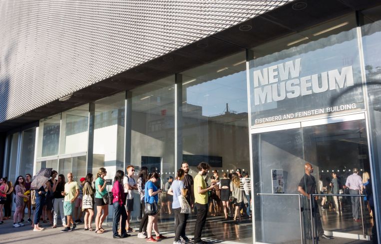 A small crowd of people lining up to enter the lobby of the New Museum in Manhattan.