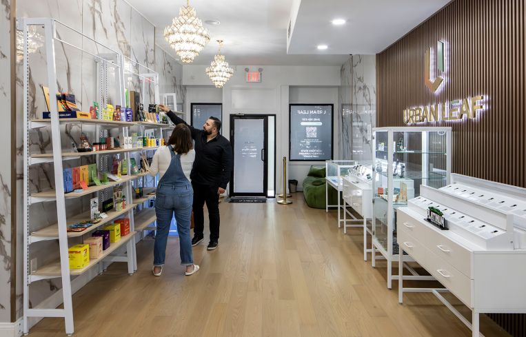 The owner of a cannabis dispensary helping a customer inside his store.