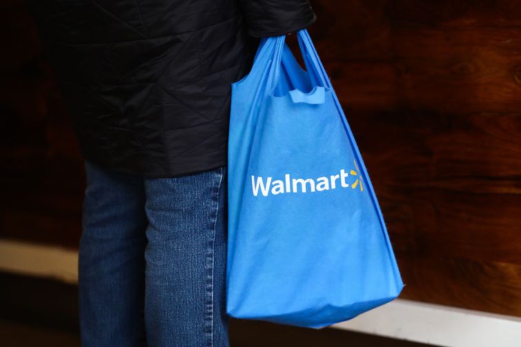 A shopper carrying a Walmart bag.