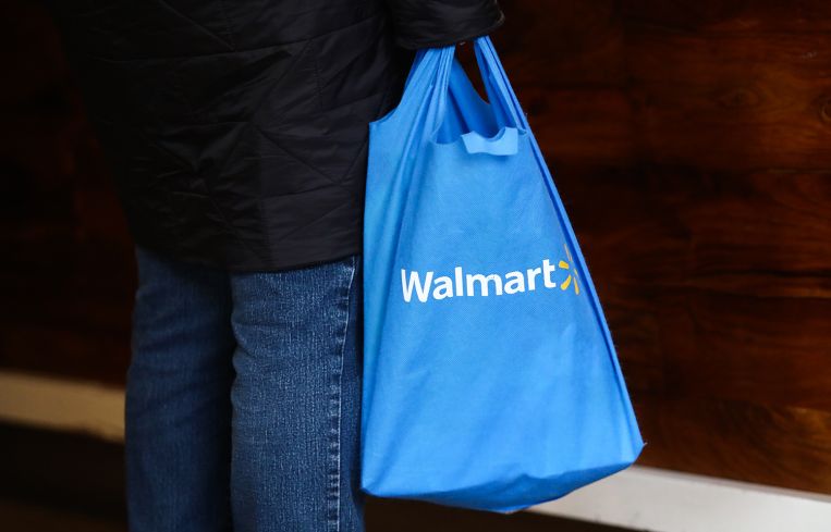 A shopper carrying a Walmart bag.