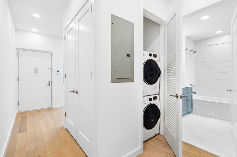 A closet with a washer/dryer unit next to a bathroom.