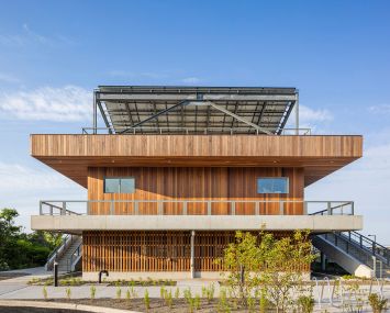 A two-story public beach facility clad in reclaimed wood.