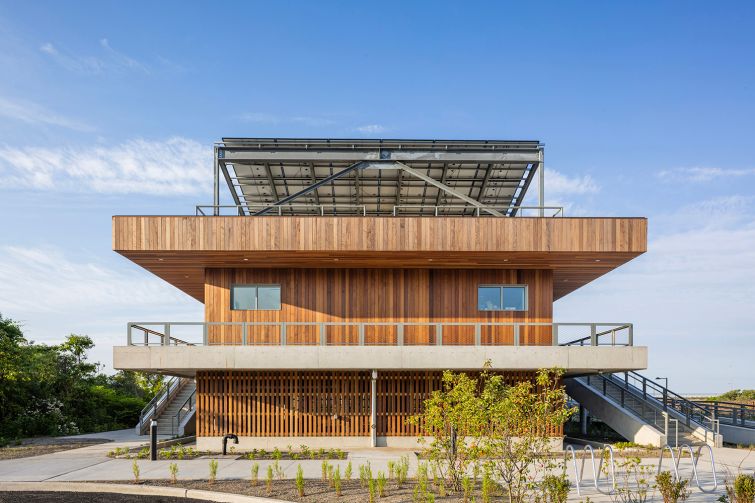 A two-story public beach facility clad in reclaimed wood.