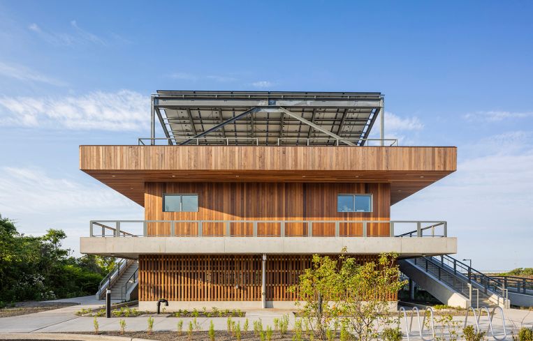 A two-story public beach facility clad in reclaimed wood.