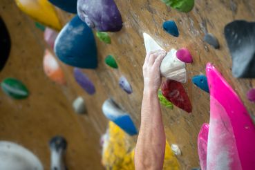 A person grabs a handhold in a climbing gym.