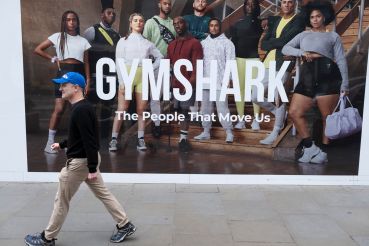 A man walks past a Gymshark billboard.