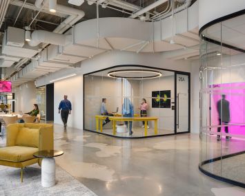 An open corridor in an office with a yellow armchair in the foreground.