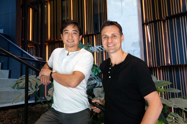 Two men leaning on a railing in T-Shirts.