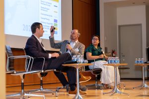 Stephen Sigmund (left) and Sheila Pozon (right) look on as Craig Schulz gestures at a slide at Commercial Observer's Public Projects Forum