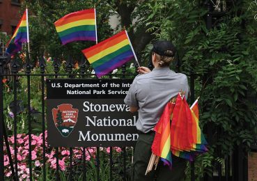 A National Park Service ranger places rainbow flags on the fence at the Stonewall National Monument in Greenwich Village
