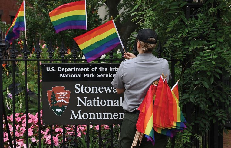 A National Park Service ranger places rainbow flags on the fence at the Stonewall National Monument in Greenwich Village.