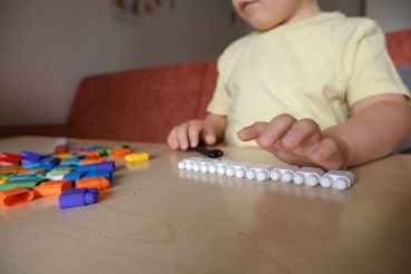 boy plays with multi-colored plastic blocks. Builds straight rows. A symptom of autism.