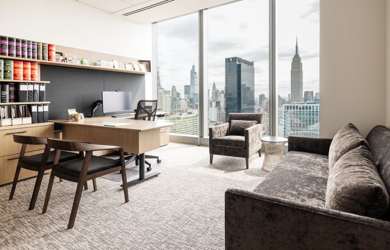 An office with a brown couch and a desk with a hutch built into the wall.