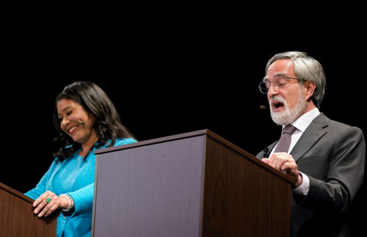 A woman and a man at podiums talking.