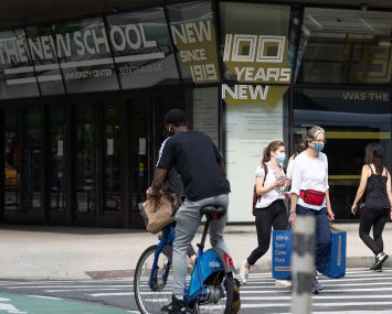 People walk in a crosswalk outside The New School's University Center on Fifth Avenue.
