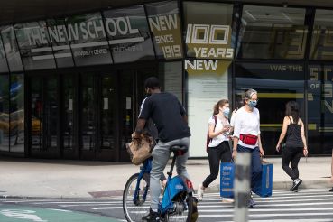 People walk in a crosswalk outside The New School's University Center on Fifth Avenue.