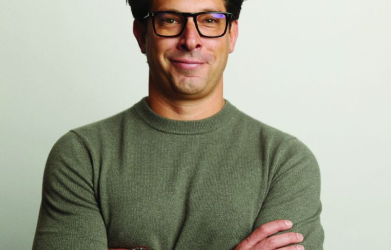 A man with glasses and his arms folded, smiling.